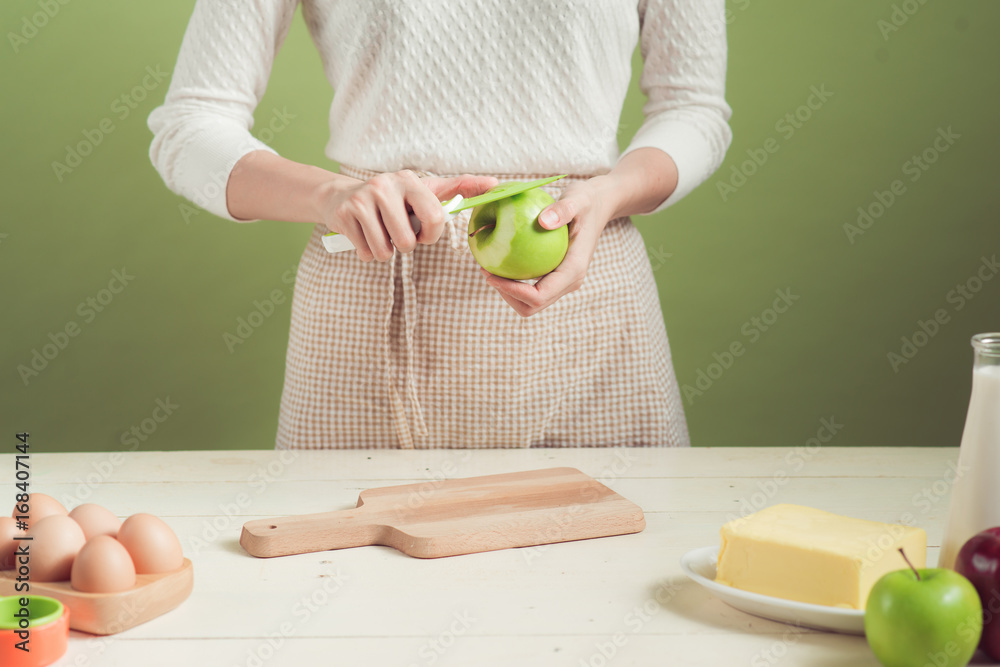 穿着围裙的家庭主妇制作。烹饪苹果蛋糕的步骤。切青苹果。