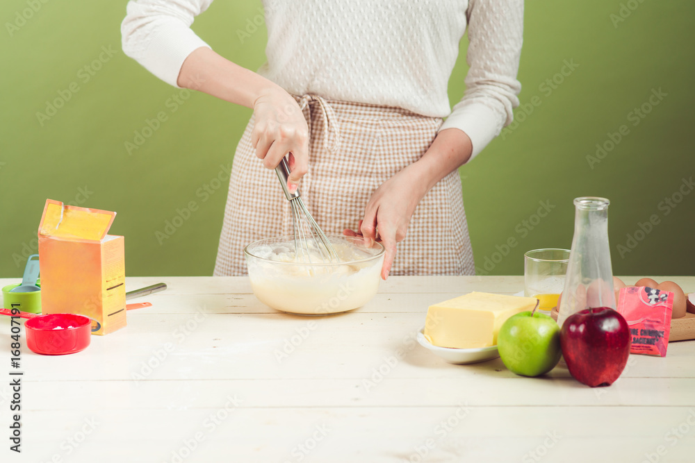 家里的妻子穿着围裙做。烹饪苹果蛋糕的步骤。切青苹果。