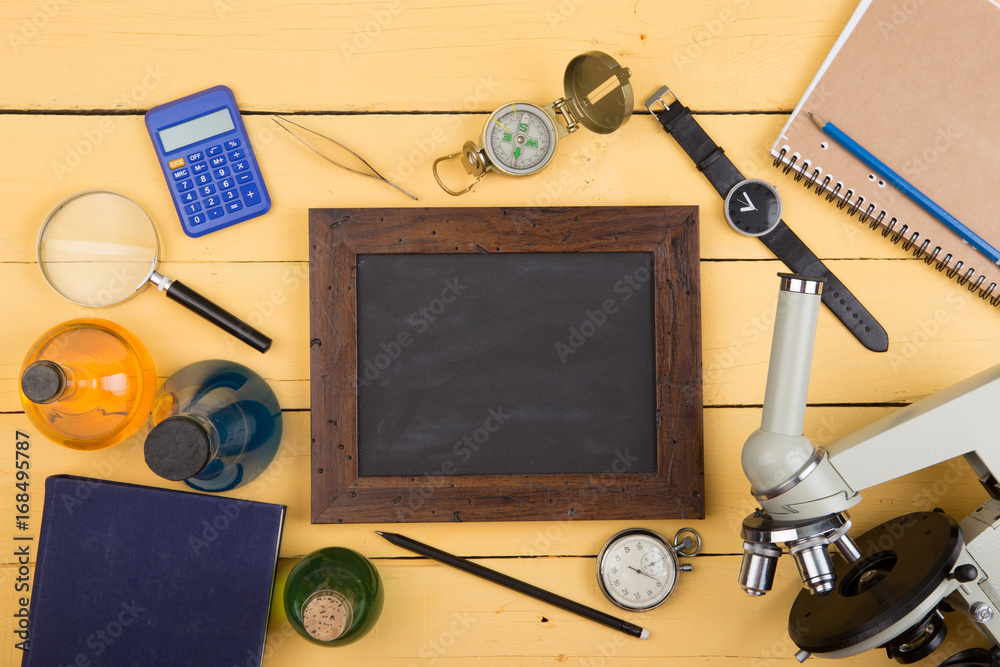 Education concept - notepad, microscope on the yellow wooden desk