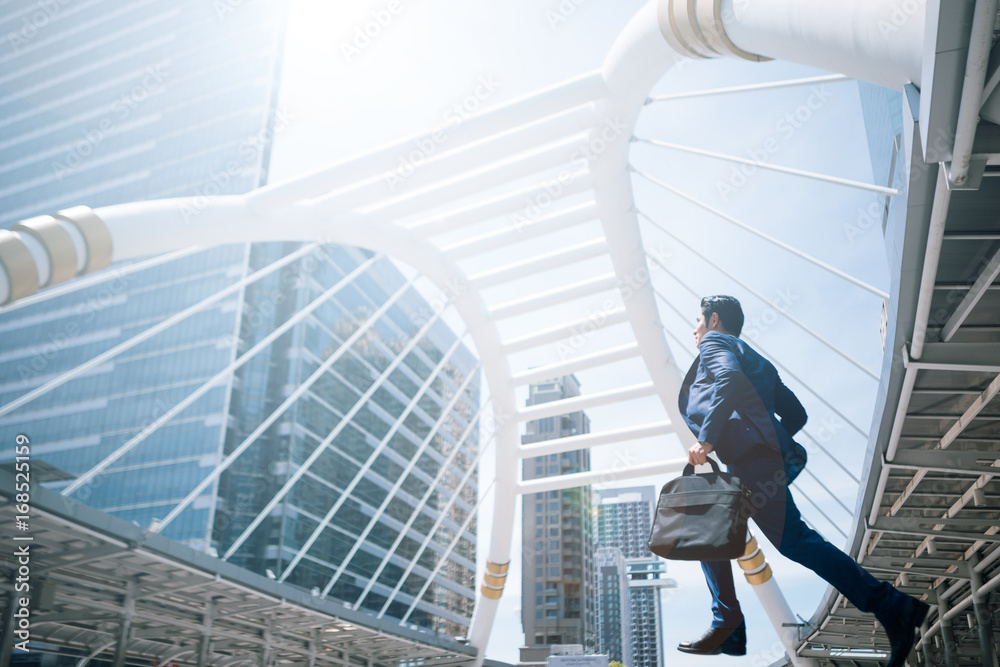 Young businessman with a briefcase running fast in a city street on a background rush hour