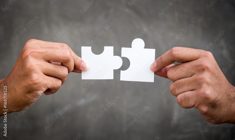 Two hands of businessman holding jigsaw/puzzle for teamwork cooperation and togetherness concept