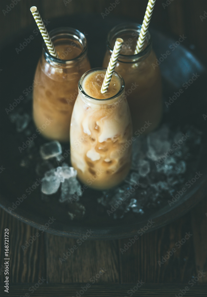 清爽的夏日饮品。装在玻璃瓶里的冷泰国冰茶，深色木棒上放着牛奶