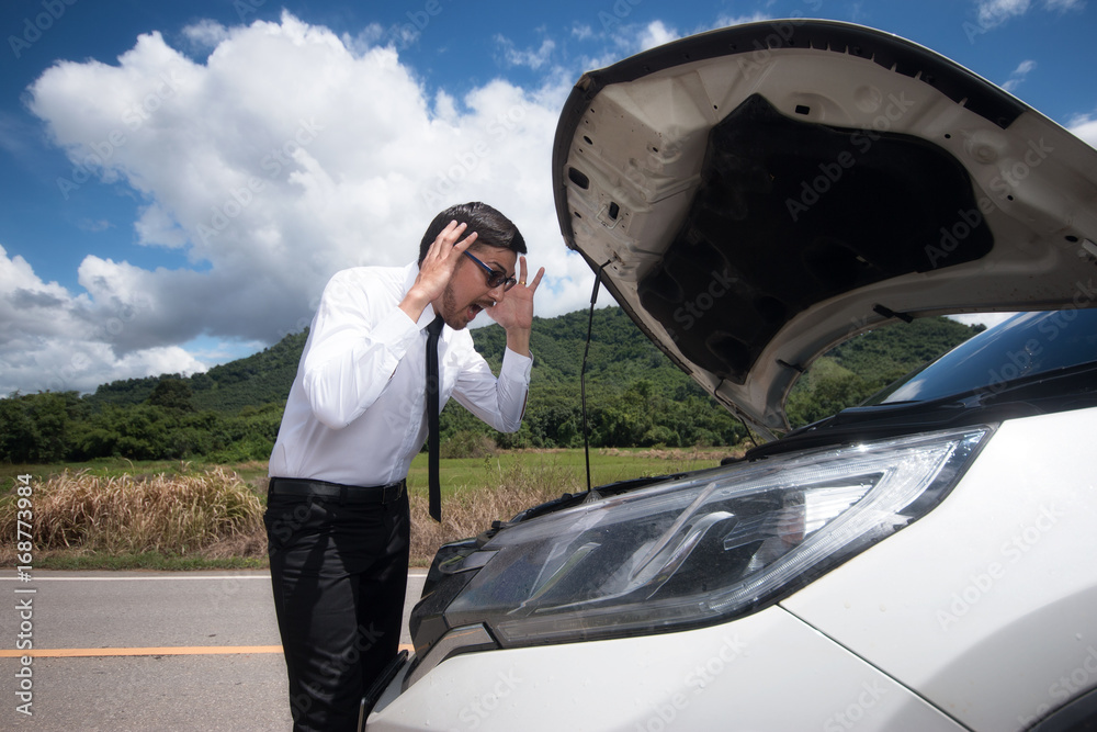 乡间街道中间有一辆破车，压力很大的年轻人。