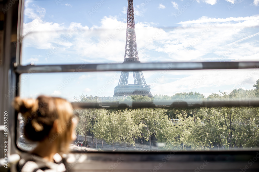 Young woman looking on the Eiffel tower through the train window in Paris. Image focused on the back