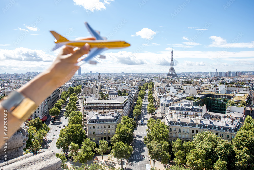 Holding a toy airplane on the Paris cityscape background. Air connection and tourism concept in the 