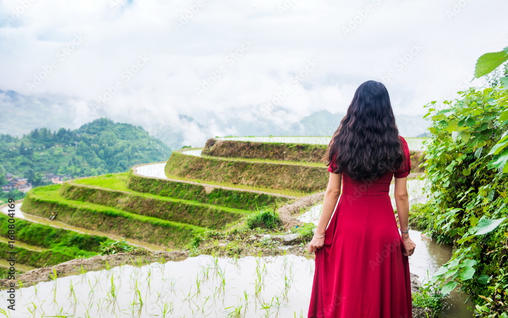 身穿红色连衣裙的女孩欣赏稻田美景