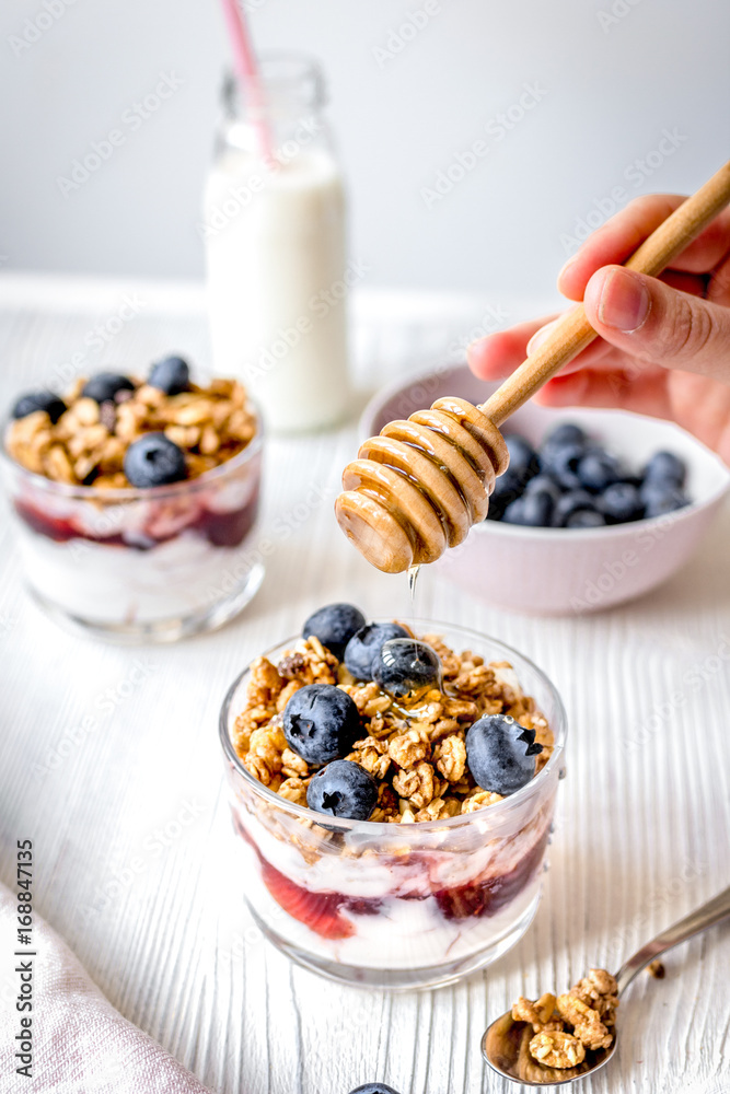 Cooking breakfast with granola and berries on white kitchen back