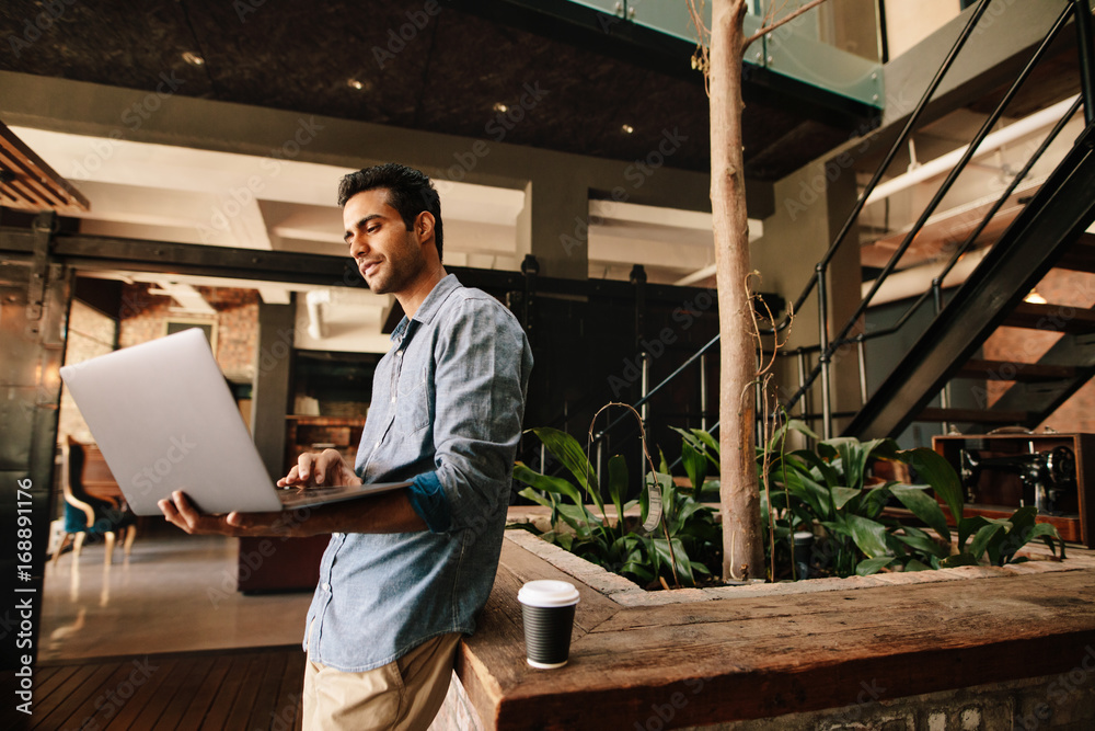 Creative man in company lounge with laptop