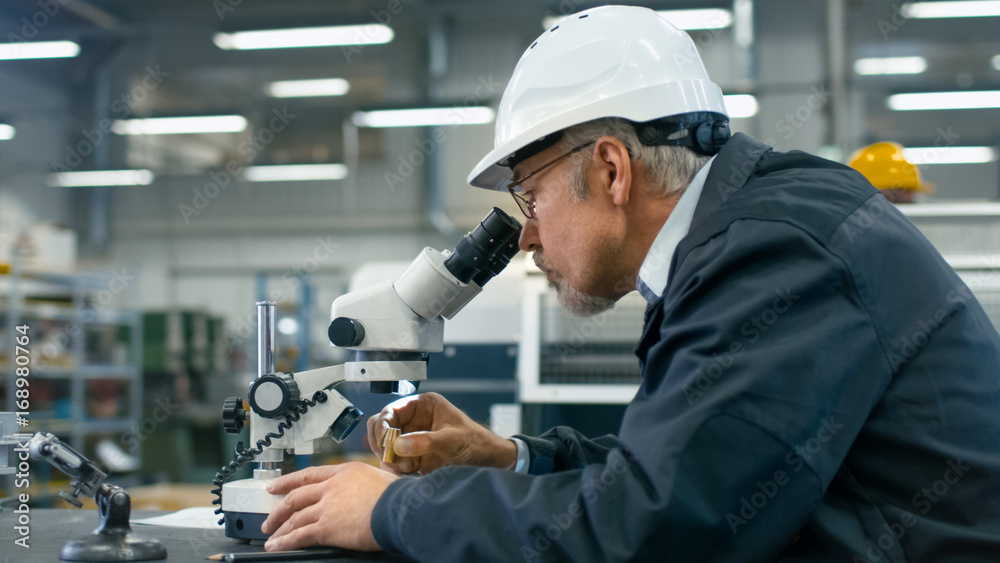 高级工程师正在工厂的显微镜下检查一个细节。