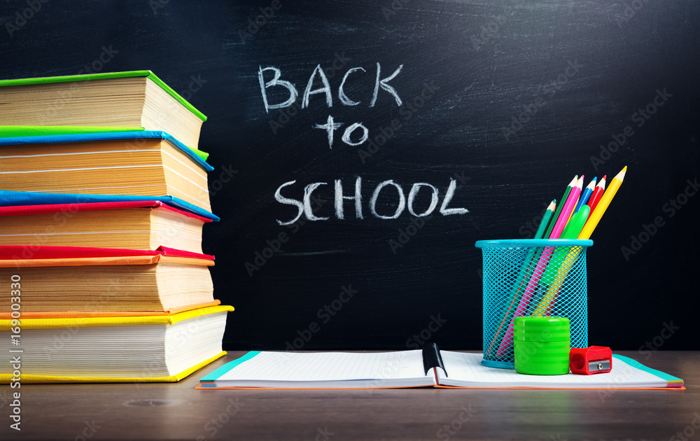 school accessories on the table with blackboard background. Pencils and books