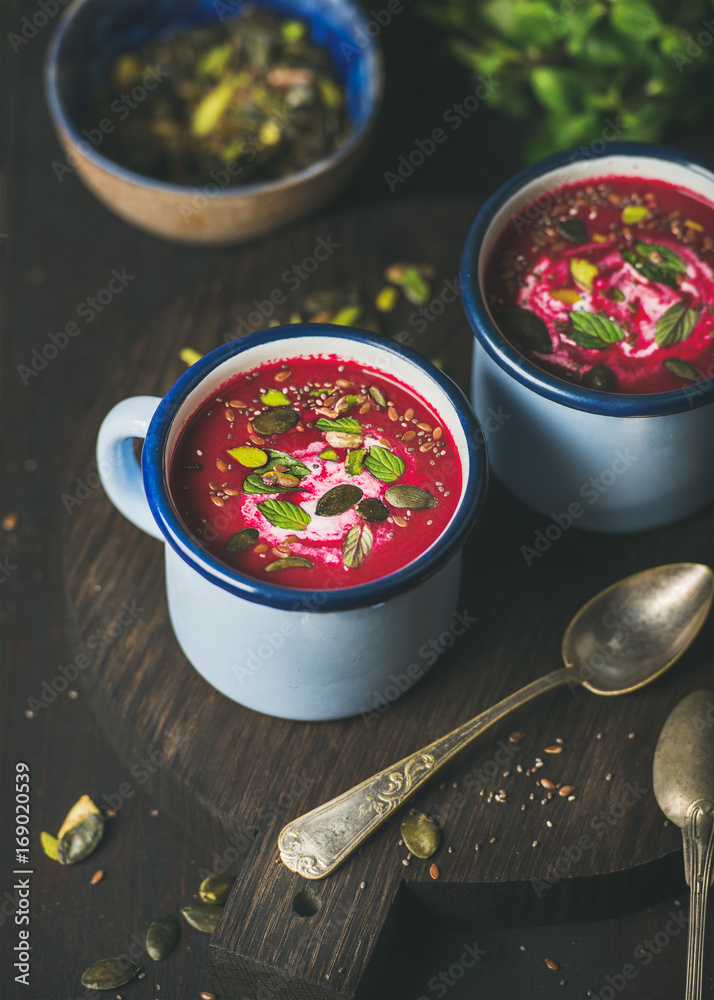 Spring detox beetroot soup with mint, pistachio, chia, flax, pumpkin seeds in blue enamel mugs over 