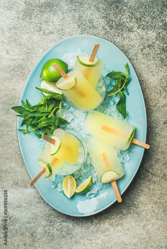 Summer refreshing lemonade popsicles with lime and mint in glasses with chipped ice on blue plate ov