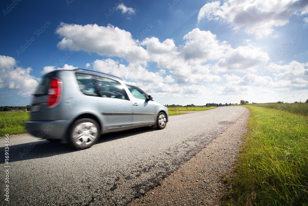 asphalt road on dandelion field with a car. vehicle moving on beautiful sunny evening