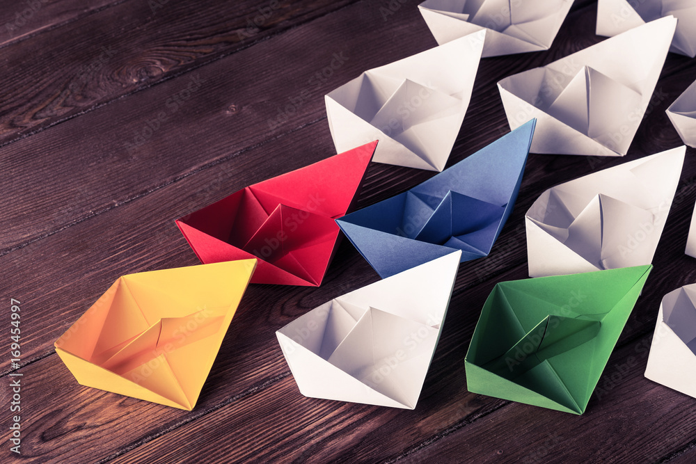 Business leadership concept with white and color paper boats on 