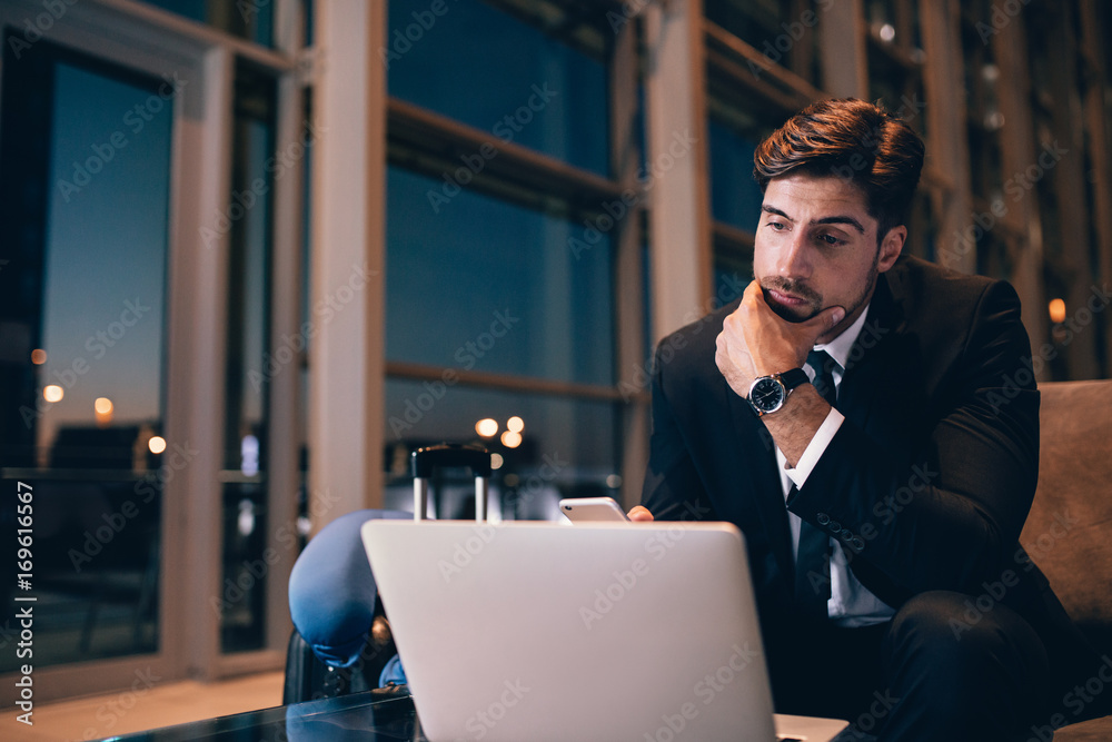 Businessman waiting at airport lounge and looking at laptop