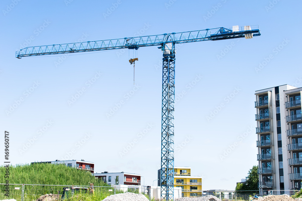 Blue construction crane in sunny day on blue sky as a background