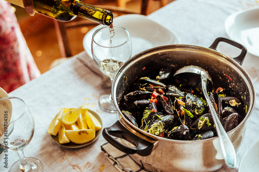 Mussels in copper pot and white wine on table. Top view.