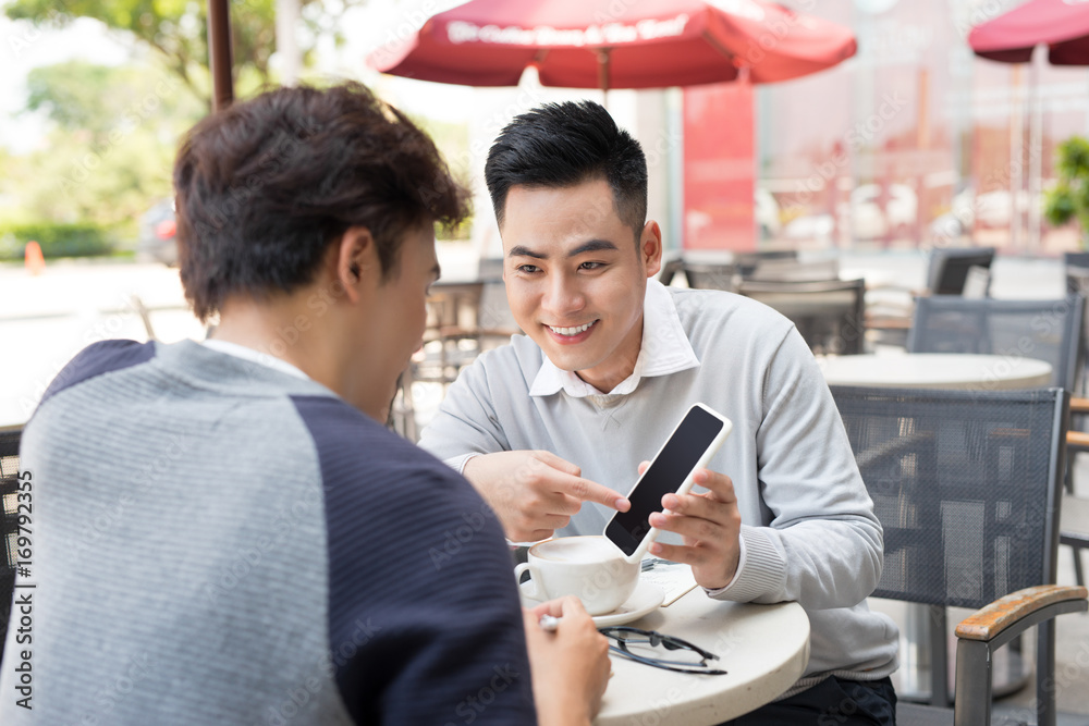 两名男子在智能手机上分享新闻、照片和视频。