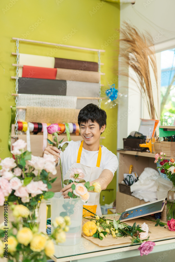 微笑的年轻亚洲花店男子在花店制作花束