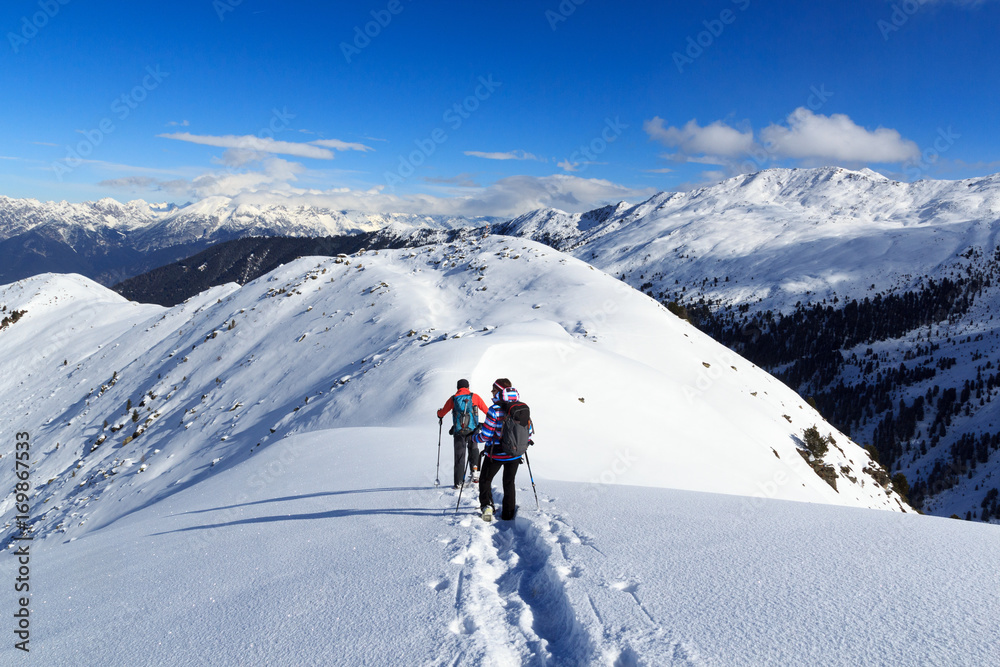 奥地利斯塔拜阿尔卑斯山，一男一女穿着雪鞋徒步旅行，蓝天下的山雪全景