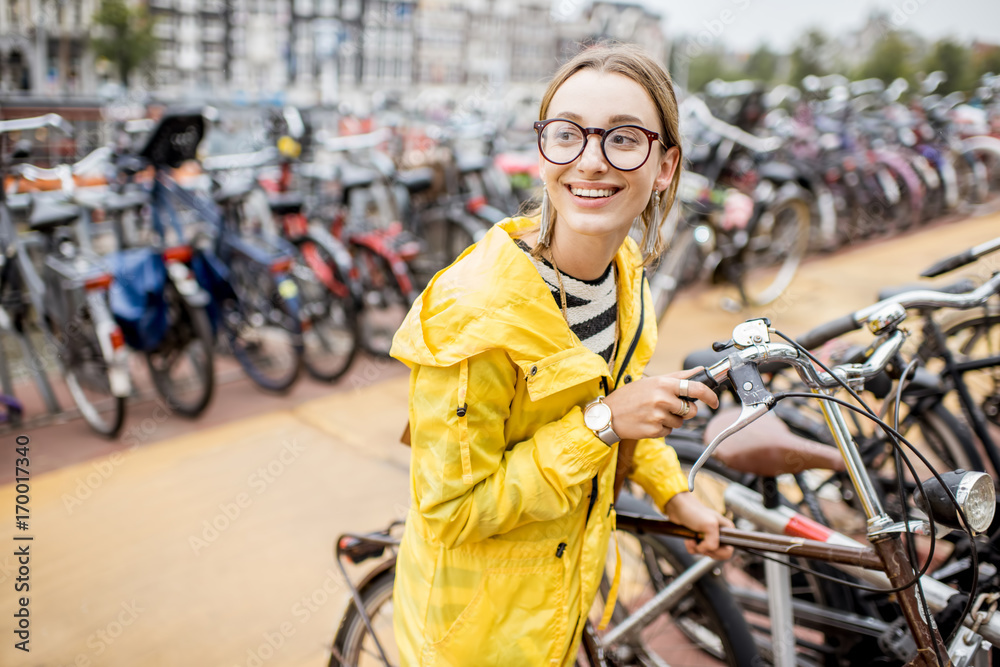 穿着黄色雨衣的年轻女游客在阿姆斯特丹的多层停车场停放自行车