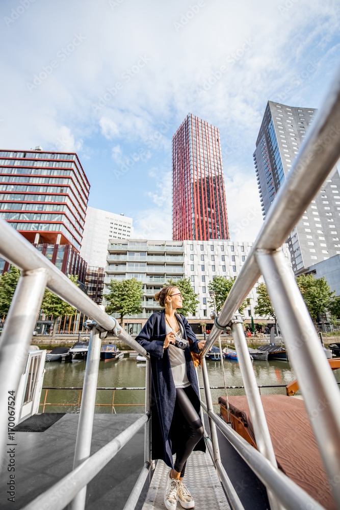 Young woman traveling at the modern harbor with skyscrapers on the background in Rotterdam city