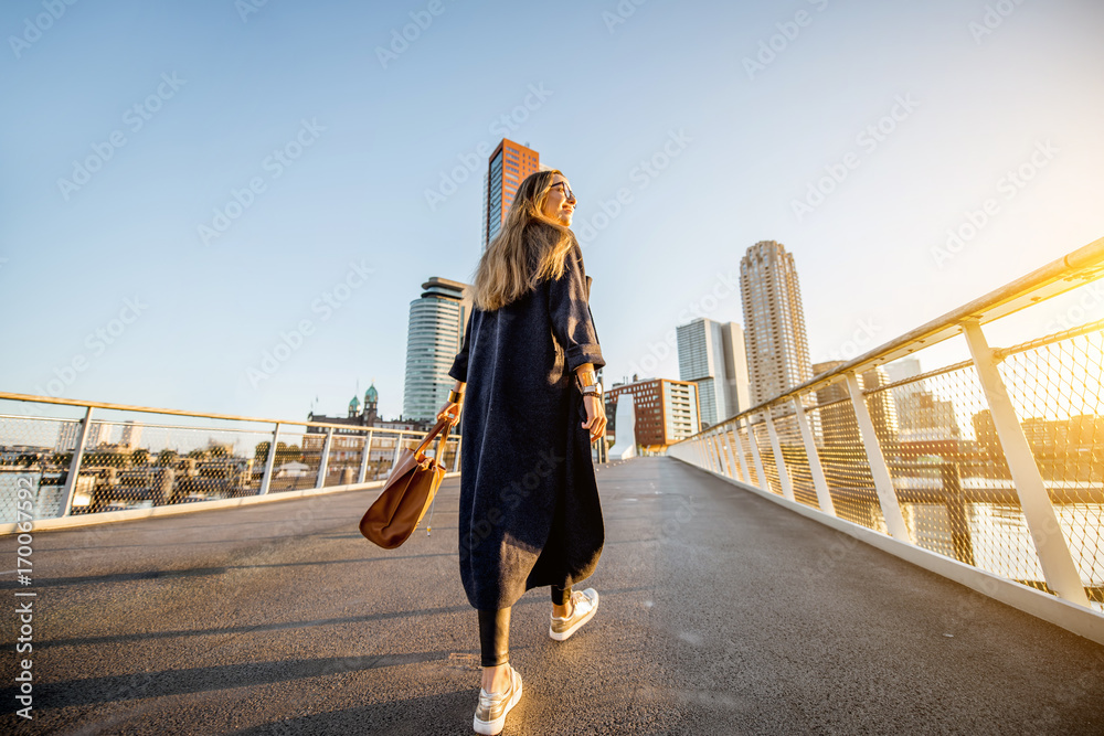 一位年轻时尚的女商人早上在Rotterd走在桥上的生活方式肖像