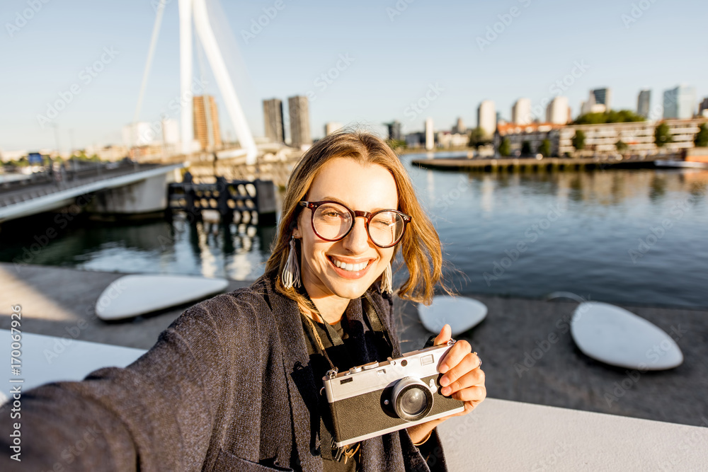 Portrait of a young woman tourist standing on the beautiful morning cityscape background in Rotterda