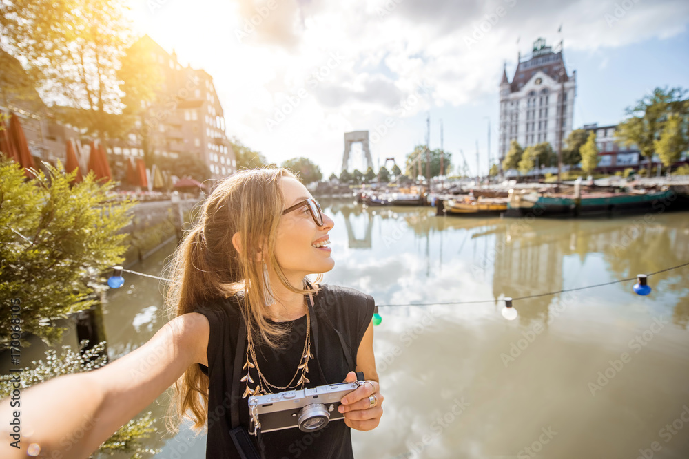 Portrait of a young woman tourist with photocamera standing at the old harbor in Rotterdam city