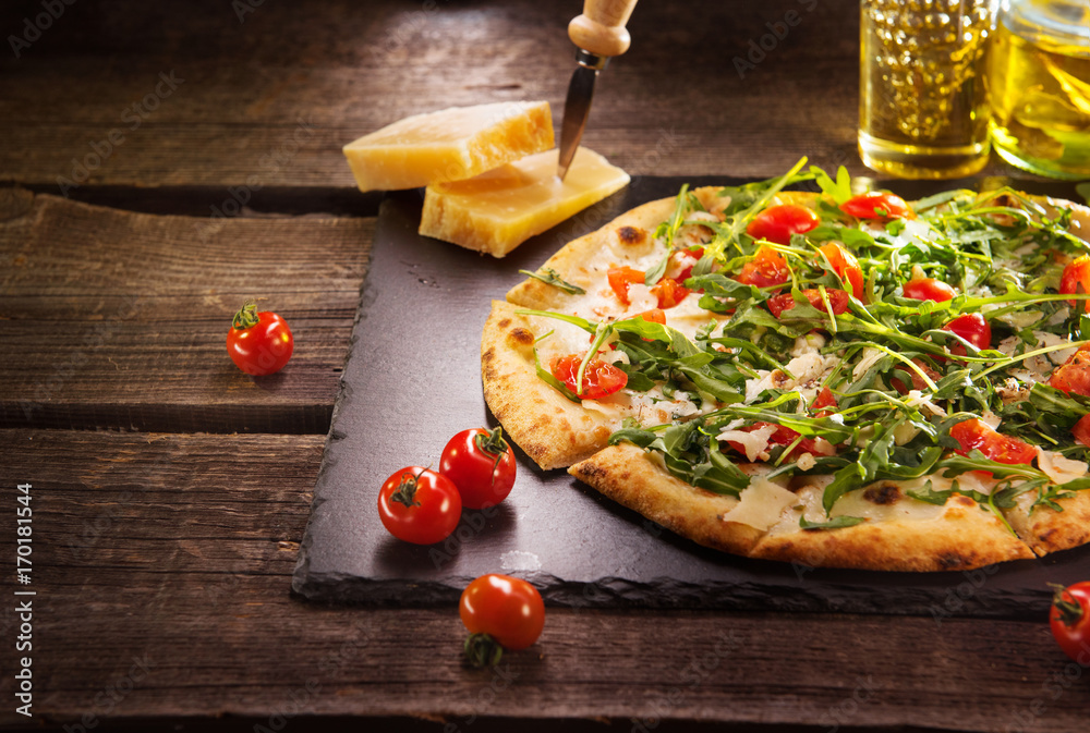 Pizza Caprese with arugula, cheese, yoghurt and cherry tomatoes closeup