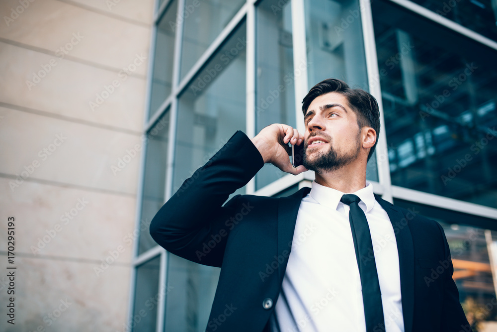 Handsome young man talking on mobile phone and looking away