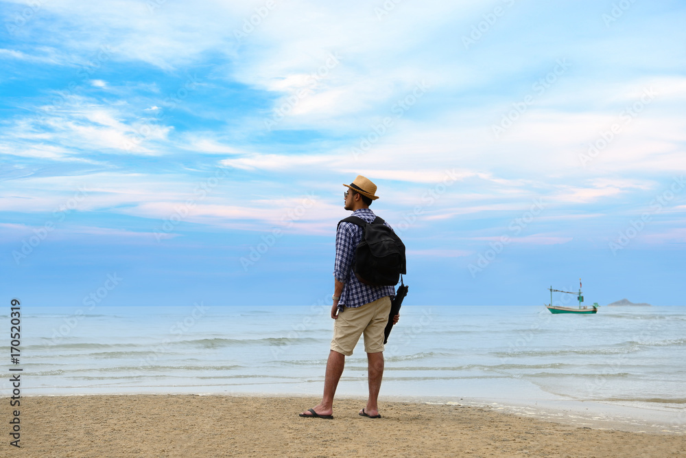 背着背包的年轻旅行者站在海边眺望大海