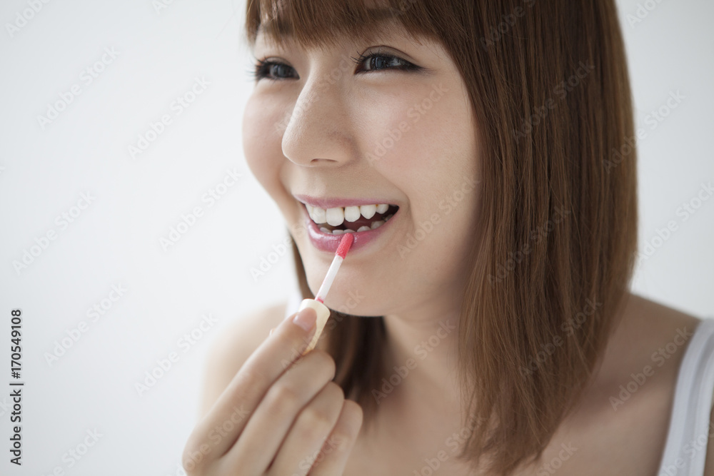 The woman is painting lipstick