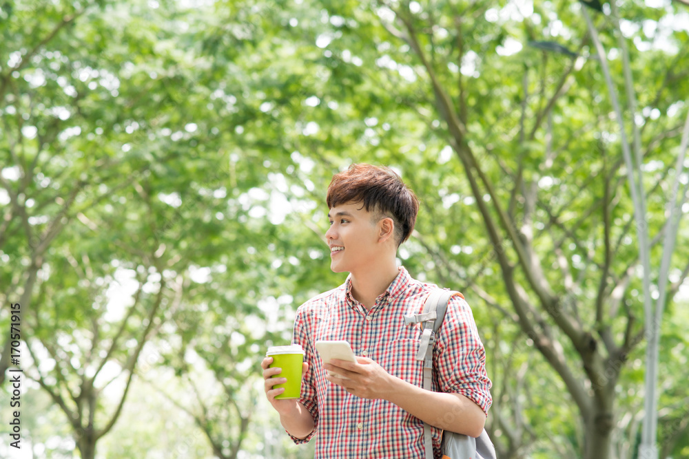 年轻的亚洲男子在公园里微笑着打电话