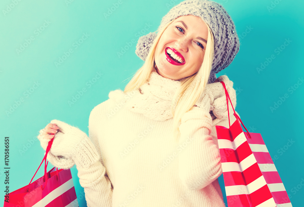 Happy young woman holding shopping bags on a blue background