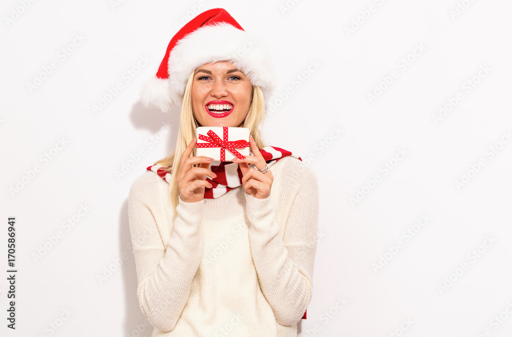 Happy young woman with Santa hat holding a Christmas present