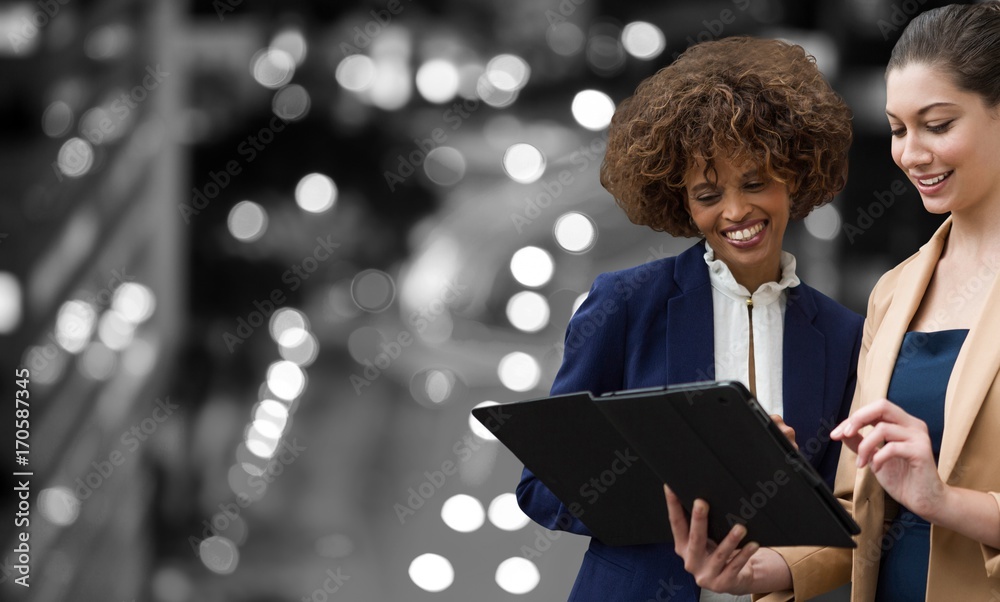 Composite image of smiling women watching tablet