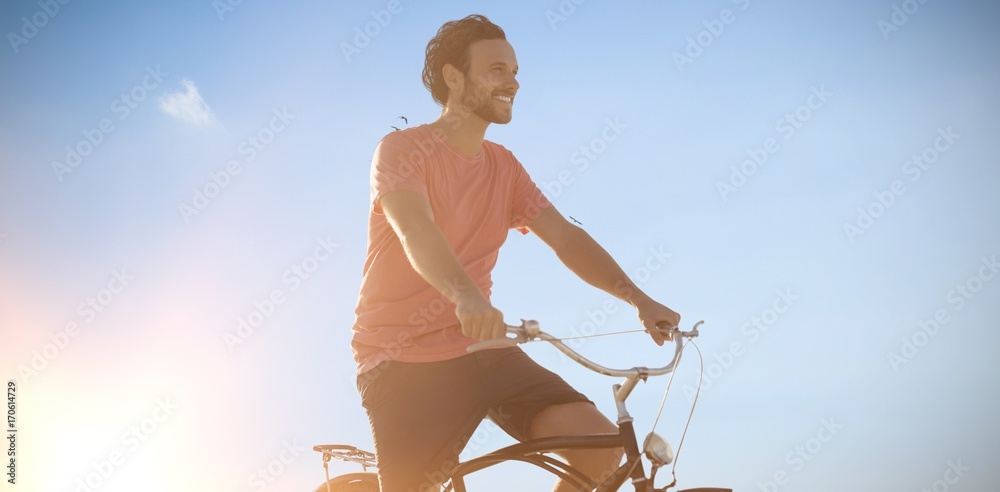 Composite image of handsome man on a bike ride on a sunny day