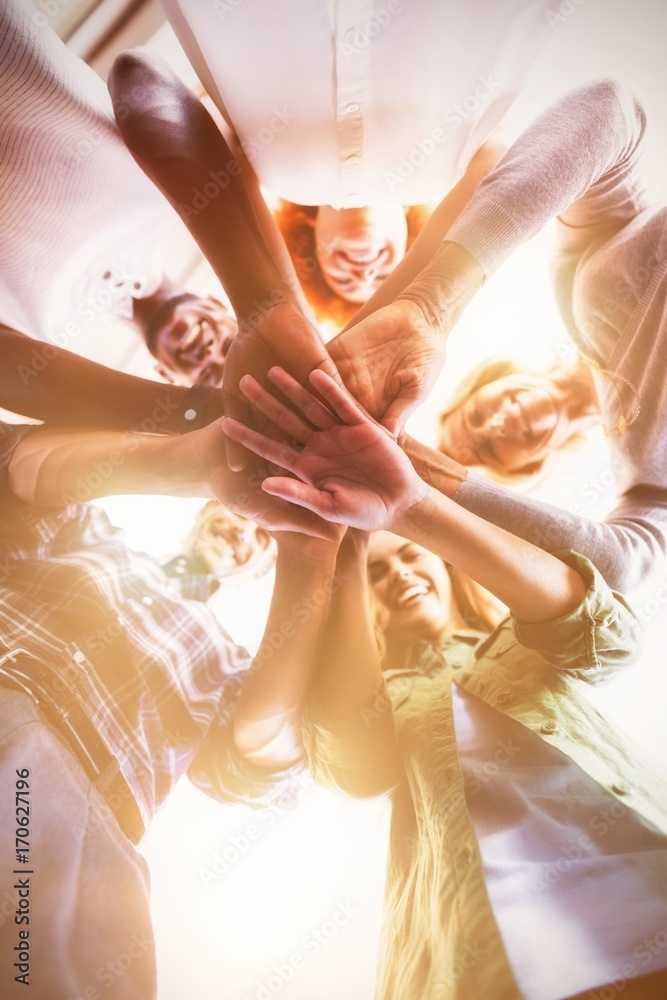 Directly below portrait of smiling business people stacking