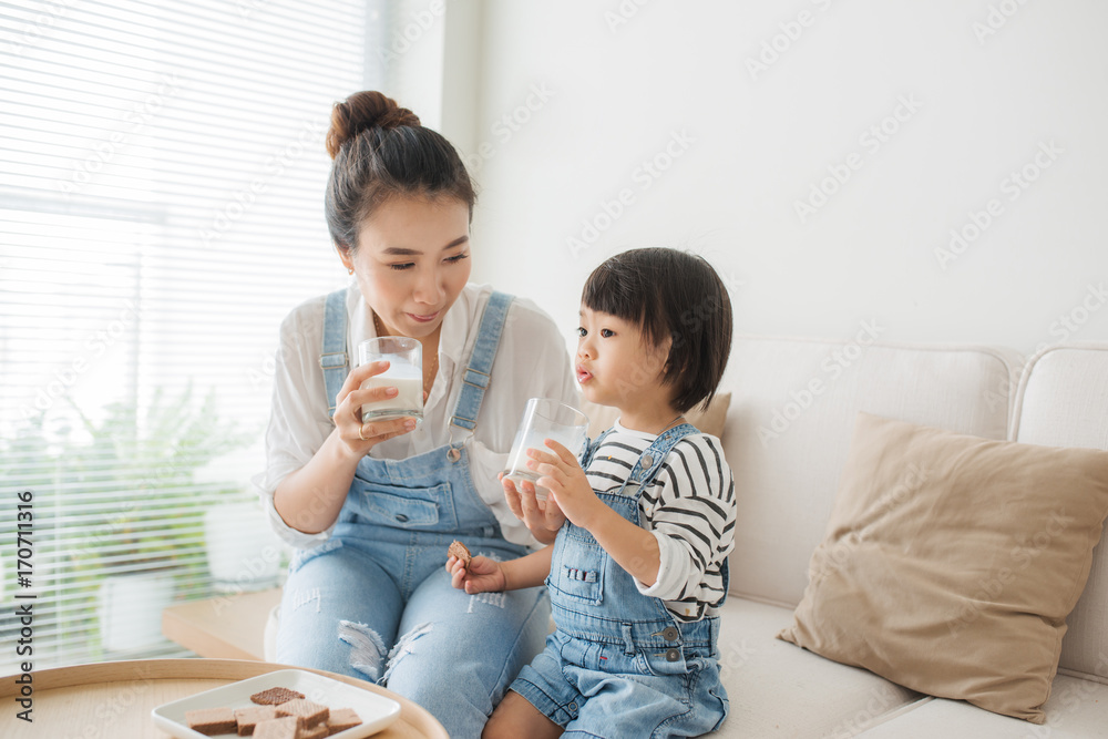 可爱的女孩和妈妈一起吃饼干喝牛奶。