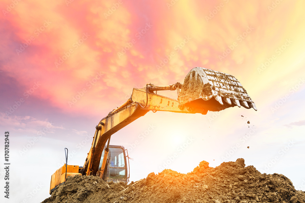 Excavator working at construction site on sunset