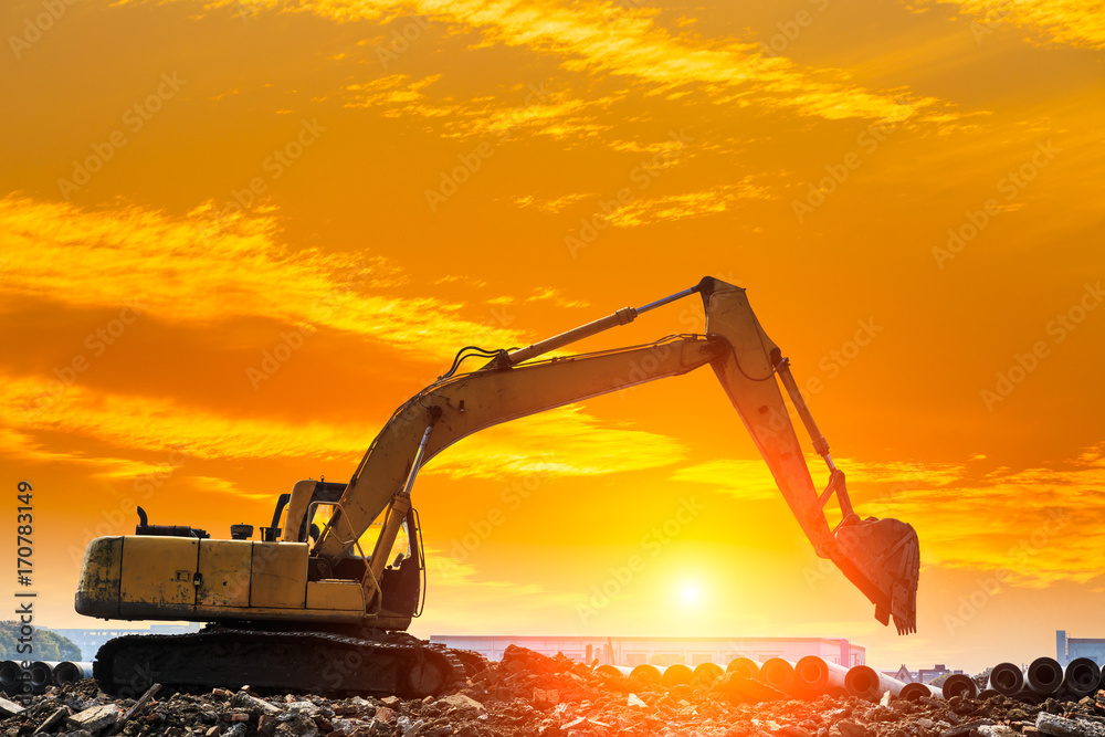 Excavator working at construction site on sunset