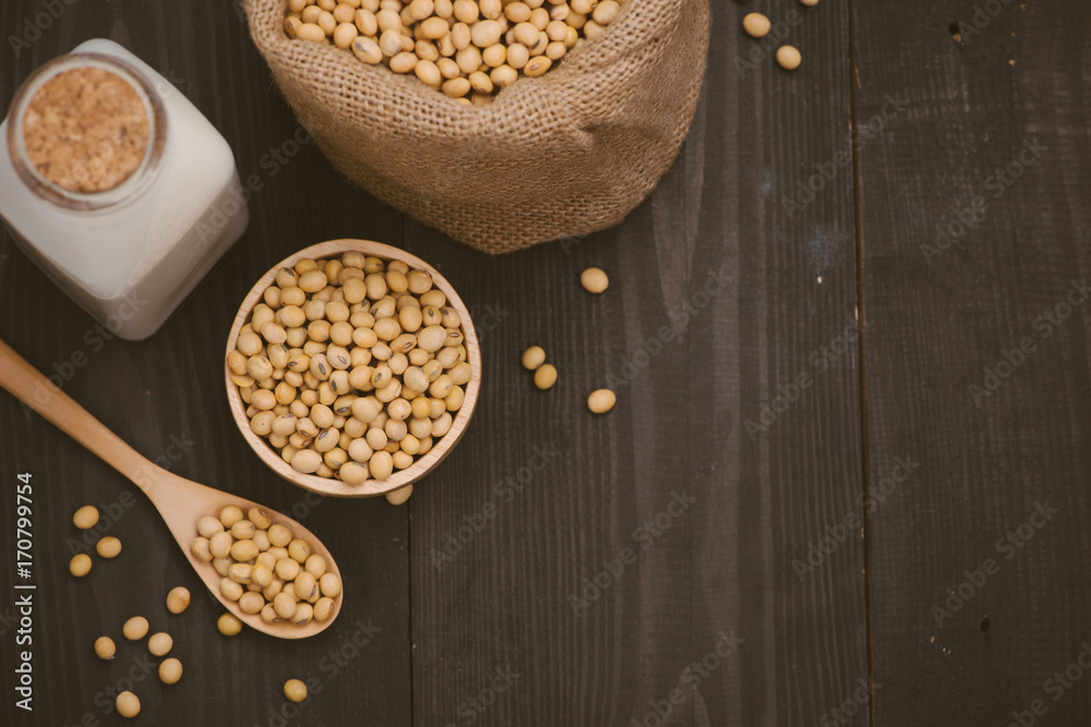 Bottle of soy milk and soybean on wooden table