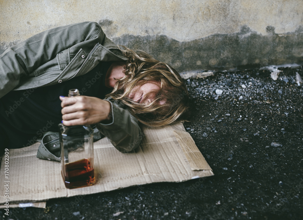 无家可归的女人抱着酒躺在地上