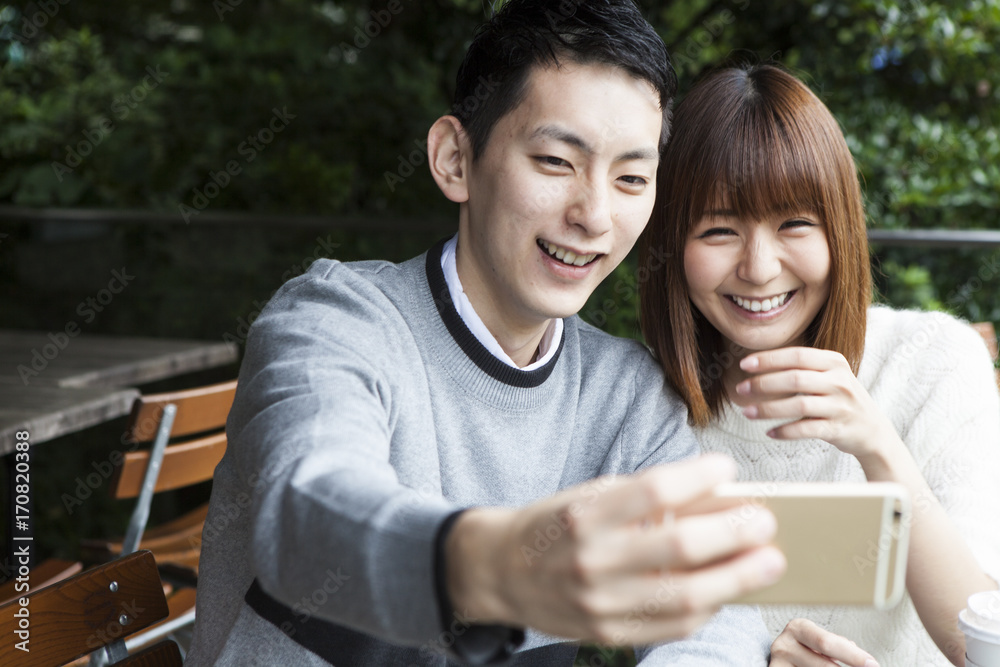 Young couple shooting pictures at the cafe terrace