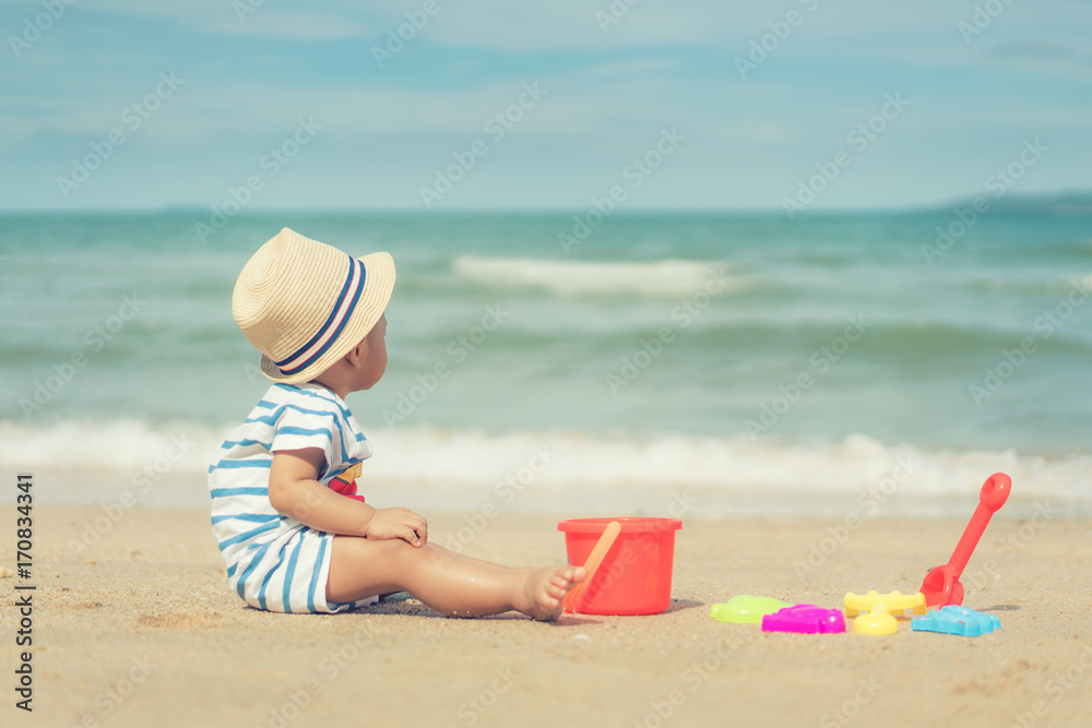 Asian 10 months baby boy playing on the sandy summer beach near the sea. Summer, Travel, Holiday con