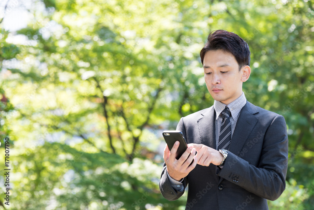 亚洲商人在公园使用智能手机