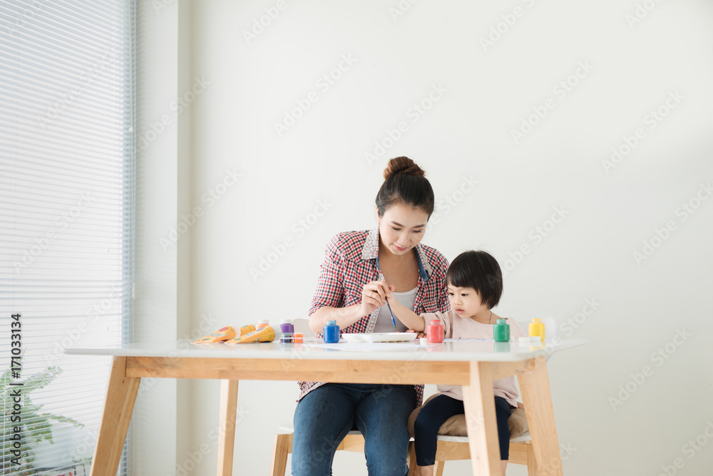 幸福的家庭，母亲和女儿一起画画。亚洲妇女帮助她的小女儿。