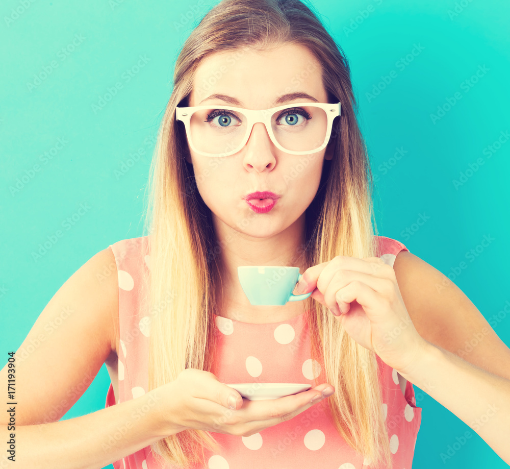 Happy young woman drinking coffee on blue background