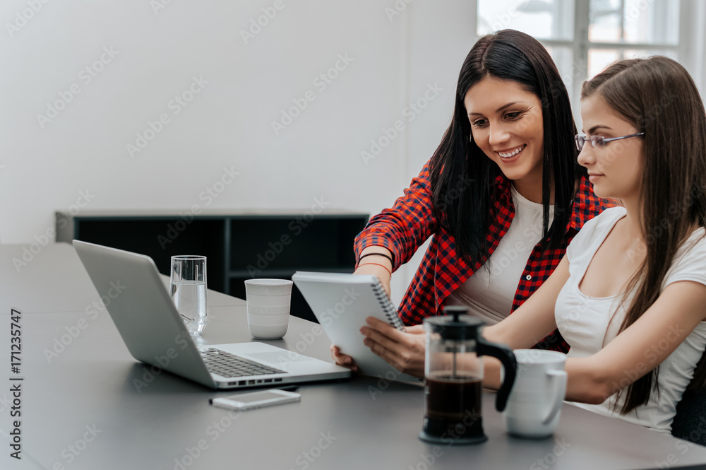 Two businesswomen working together at desk at office.